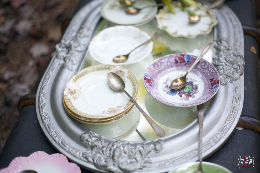 mismatched china and heirloom silverware sit on top mirror, whimsical wedding photography inspiration