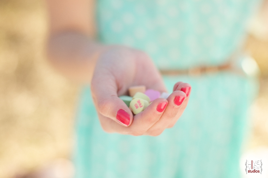 woman with pretty pink nails holding colorful sweetheart candies
