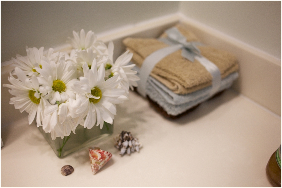 brown, blue, and tan terry washcloths tied with light blue ribbon, fresh flowers and sea shells as an affordable decoration to bathroom sink