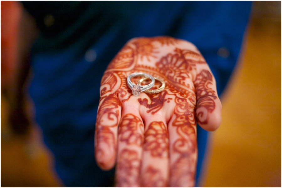 bride with henna hand tattoos holding out wedding rings