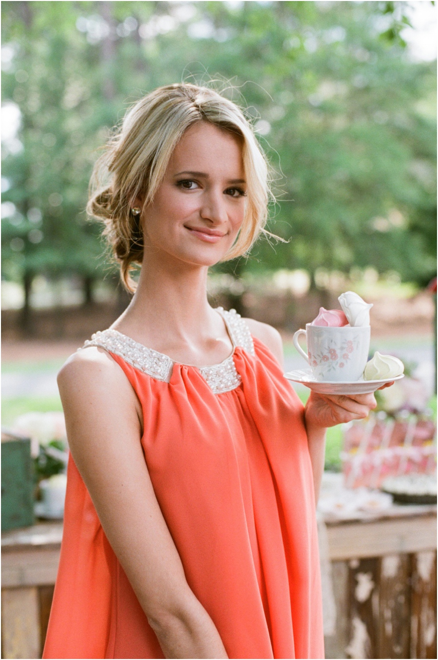 bridesmaid in coral dress holding vintage teacup with colorful meringues, southern wedding photographers