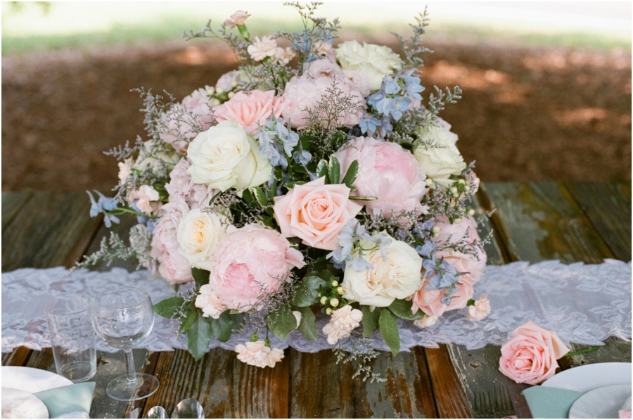 lush floral arrangement of peach and cream roses and pink peonies made by Embellished Blooms was set atop a vintage lace table runner for a centerpiece, rustic wedding photographers